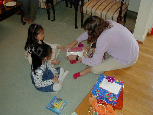 The girls help open the presents.